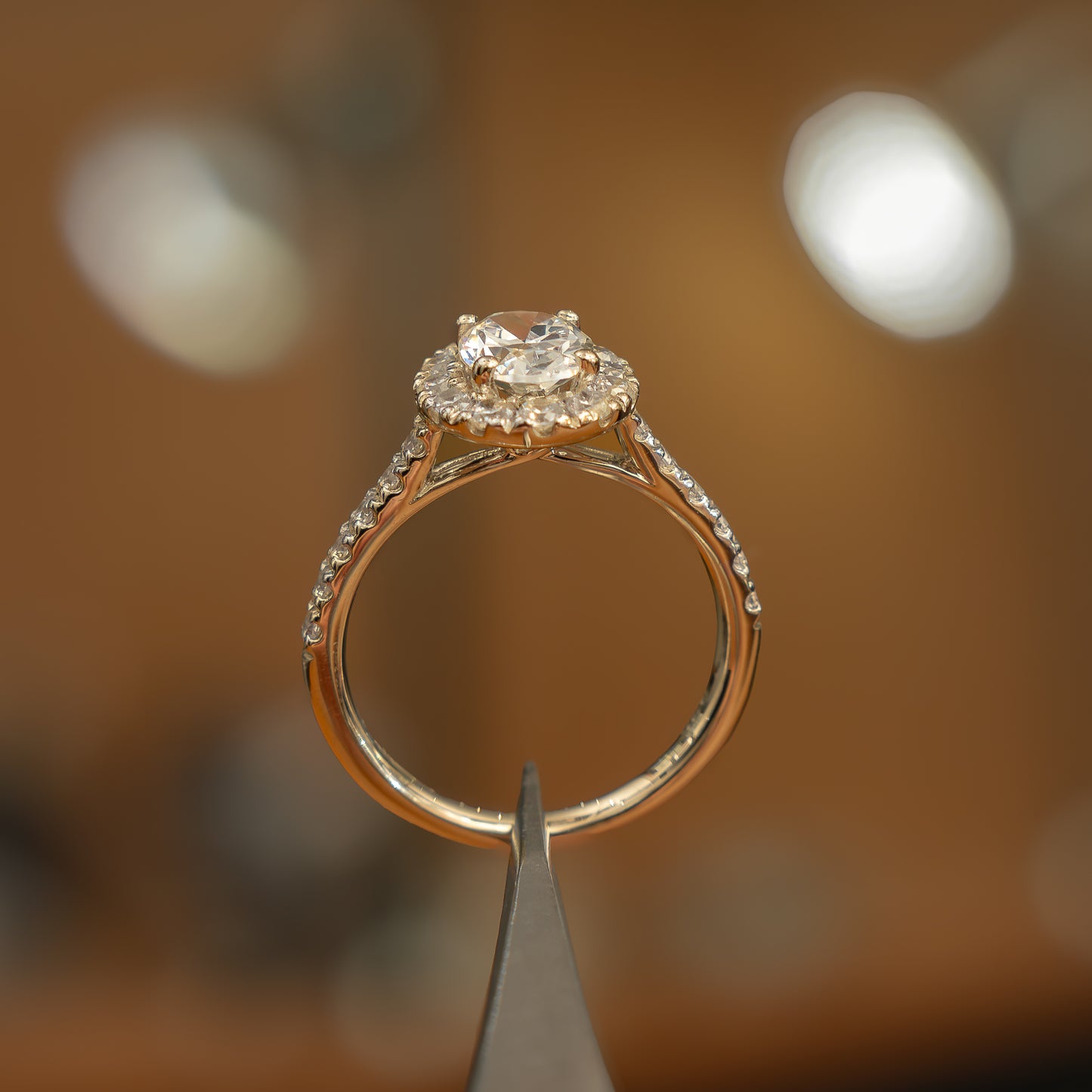 studio shot of luxury oval yellow gold diamond set shoulders halo lab grown diamond engagement ring