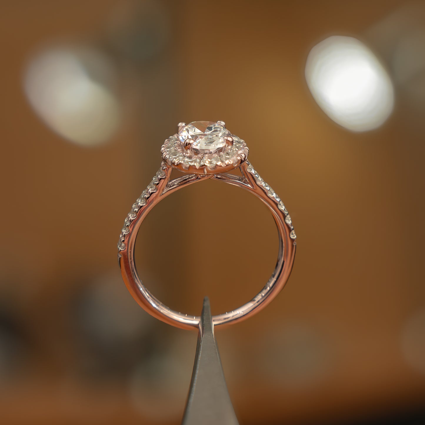 studio shot of luxury rose gold diamond set shoulders halo lab grown diamond engagement ring