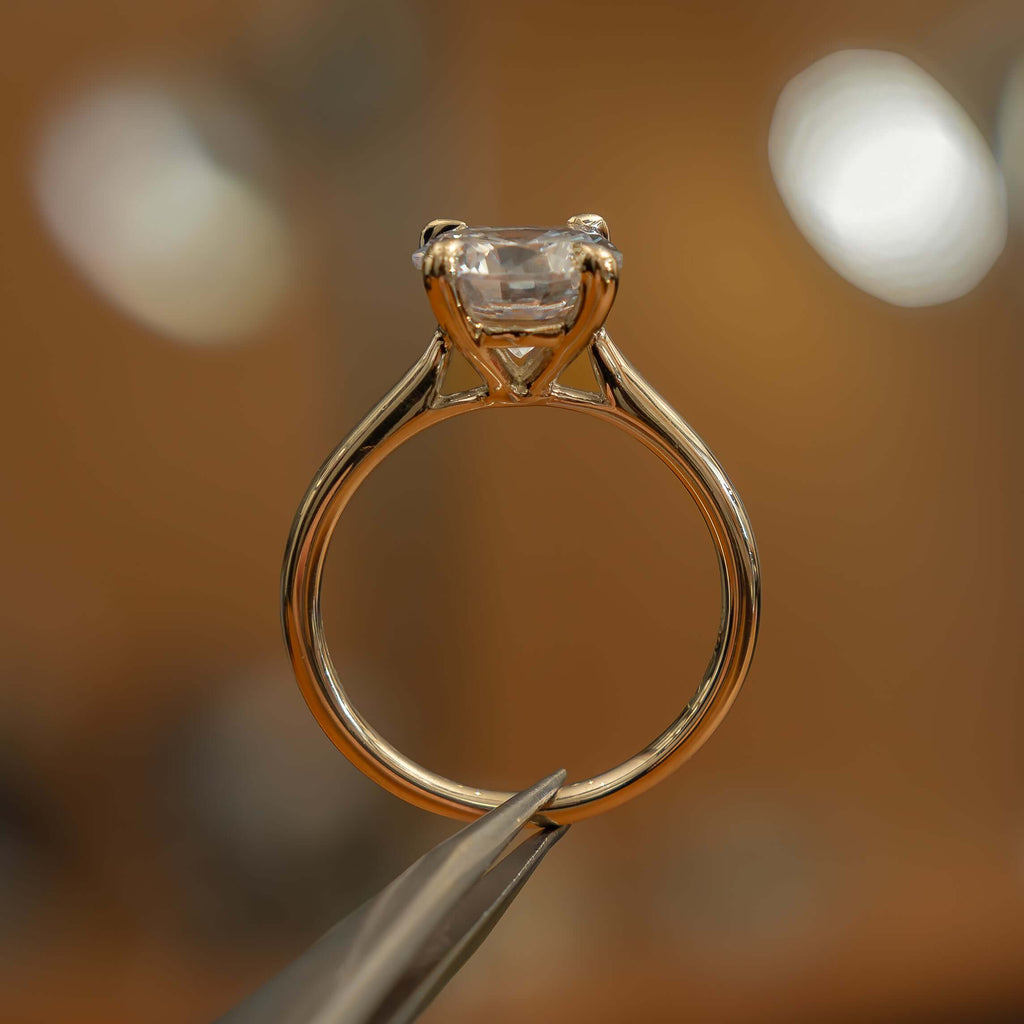 studio side image of luxury round yellow gold diamond set shoulders lab grown diamond engagement ring